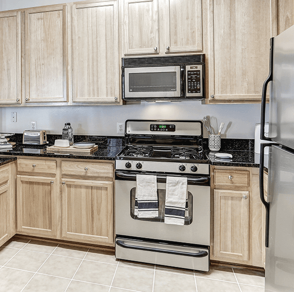 kitchen with stainless steel appliances, gas cooking, granite counter tops and tile flooring - luxury apartments in ashburn va