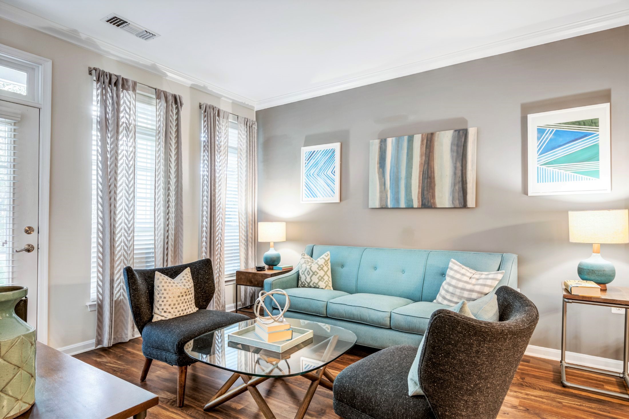 living space with sofa, coffee table, chairs, end table, modern artwork and view of balcony at jefferson arbors at broadlands luxury apartments in ashburn va